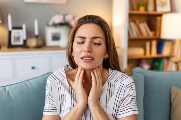Close up of young woman rubbing her inflamed tonsils, tonsilitis problem, cropped. Woman with thyroid gland problem, touching her neck, girl has a sore throat
